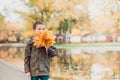 Happy kid boy walking in the Park . Lots of yellow leaves around.The boy is wearing a brown jacket