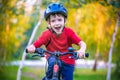 Happy kid boy of 6 years having fun in autumn forest with a bicycle on beautiful fall day. Active child making sports. Safety, sp Royalty Free Stock Photo