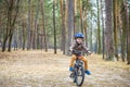 Happy kid boy of 3 or 5 years having fun in autumn forest with a bicycle on beautiful fall day. Active child wearing bike helmet. Royalty Free Stock Photo