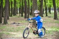 Happy kid boy of 4 years having fun in autumn or summer forest with a bicycle Royalty Free Stock Photo