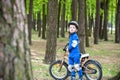 Happy kid boy of 4 years having fun in autumn or summer forest with a bicycle on beautiful fall spring day. Active child making sp
