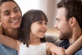 Happy kid daughter embracing parents looking at smiling mom