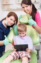 Happy kid at dentist playing with wireless tablet Royalty Free Stock Photo