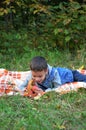 Happy kid eating fruits. happy cute child boy eating an apple. lies on a coverlet in an autumn park Royalty Free Stock Photo