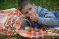 Happy kid eating fruits. happy cute child boy eating an apple. lies on a coverlet in an autumn park Royalty Free Stock Photo