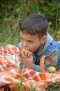 Happy kid eating fruits. happy cute child boy eating an apple. lies on a coverlet in an autumn park Royalty Free Stock Photo