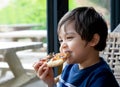 Happy Kid eating home made pizza in the cafe, Cute little Child  boy biting off big slice of fresh made pizza in the restaurant, Royalty Free Stock Photo