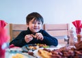 Happy kid eating sunday dinner at home, Child boy having Chirstmas lunch with family