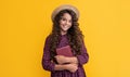 happy kid with frizz hair hold book on yellow background