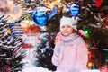 happy kid girl with christmas candy. Winter holiday portrait at christmas tree decorated with toys Royalty Free Stock Photo