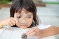 Happy kid girl exploring nature with a magnifying glass and a snail. He having fun in the garden. The concept of the kid is ready Royalty Free Stock Photo