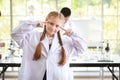 Happy kid girl making science experiments and confident. she pose thinking of something with another kids blurred background Royalty Free Stock Photo