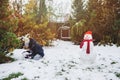 Happy kid girl making snow man on Christmas vacations on backyard