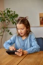 Happy kid girl playing game on mobile phone at home Royalty Free Stock Photo