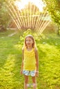 Happy kid girl playing with garden sprinkler run and jump, summer Royalty Free Stock Photo