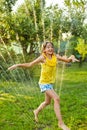 Happy kid girl playing with garden sprinkler run and jump, summer Royalty Free Stock Photo