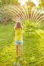 Happy kid girl playing with garden sprinkler run and jump, summer Royalty Free Stock Photo