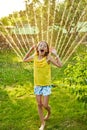 Happy kid girl playing with garden sprinkler run and jump, summer Royalty Free Stock Photo