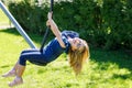 Happy kid girl rids on zip line swing outdoor game play equipment on playground. Child having fun outdoors. Preschool