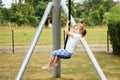 Happy kid girl rids on zip line swing outdoor game play equipment on playground. Child having fun outdoors. Preschool