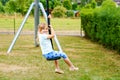 Happy kid girl rids on zip line swing outdoor game play equipment on playground. Child having fun outdoors. Preschool