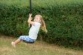 Happy kid girl rids on zip line swing outdoor game play equipment on playground. Child having fun outdoors. Preschool