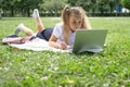 happy kid girl on school uniform with notebook has online lesson on laptop on lawn