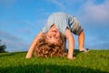 Happy kid girl standing upside down on her head on grass in summer day. Royalty Free Stock Photo