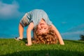 Happy kid girl standing upside down on her head on grass in summer day. Royalty Free Stock Photo