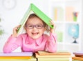 Happy kid in glasses under roof made from book