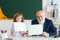 Happy kid with grandfather hold paper board. Senior Teacher help to learn. Education, teachering, elementary school. Royalty Free Stock Photo