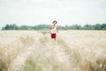 Happy kid in hat and red shorts race along a country road in the wheat field Royalty Free Stock Photo