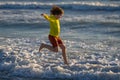 Happy kid have fun on tropical sea beach resort. Funny baby boy run with splashes by water pool along surf edge. Active Royalty Free Stock Photo