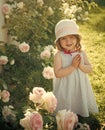 Happy kid having fun. Child smiling at blossoming rose flowers on green grass Royalty Free Stock Photo