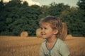 Happy kid having fun. Little child smile at field with hay bales, agriculture