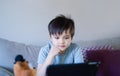 Happy kid having fun watching cartoon or play game on tablet, School boy using digital pad searching the ideas on internet for his Royalty Free Stock Photo
