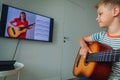 Happy kid having guitar lesson online, distant learning