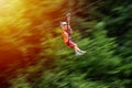 Happy kid with helmet and harness on zip line between trees. Panning effect Royalty Free Stock Photo