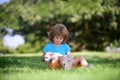 Happy kid hugging beautiful puppy dog. Young boy kid playing with puppy and sitting on grass. Cute boy child with her Royalty Free Stock Photo