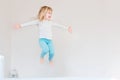 Happy kid jumping over bed. Cute little blond girl having fun indoors. Happy and careless childhood concept Royalty Free Stock Photo