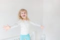 Happy kid jumping over bed. Cute little blond girl having fun indoors. Happy and careless childhood concept