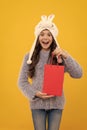 happy kid long hair in hat hold pack on yellow background, new year