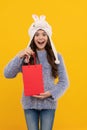 happy kid long hair in hat hold pack on yellow background, new year