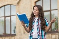 Happy kid with long wavy hair in casual style read library book preparing for school lesson outdoors, literature