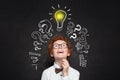 Happy kid looking at lightbulb on blackboard background. Brainstorming and idea concept Royalty Free Stock Photo