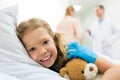 happy kid lying on hospital bed while mother talking
