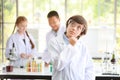 Happy kid making science experiments and confident. he pose thinking of something with another kids blurred background education Royalty Free Stock Photo