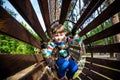 Happy kid overcomes obstacles in rope adventure park. Summer holidays concept. Little boy playing at rope adventure park. Modern Royalty Free Stock Photo