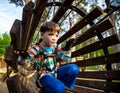 Happy kid overcomes obstacles in rope adventure park. Summer holidays concept. Little boy playing at rope adventure park. Modern Royalty Free Stock Photo