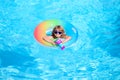 Happy kid playing with colorful swim ring in swimming pool on summer day. Child water toys. Children play in tropical Royalty Free Stock Photo